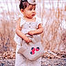 toddler, child, party_hat, white_outfit, bag, strawberries, outdoor, nature, curious, standing, young_child, fashion, cute, portrait, person, grass, ground, daylight, casual, accessory