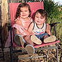 children, smiling, outdoor, chair, red_chair, grass, wood, sunlight, happy, cute, siblings, portrait, dress, tank_top, shoes, nature, daylight, rustic, plants, dirt