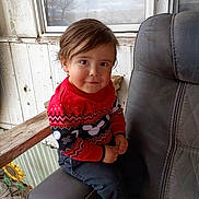 Jose is registered to the contest to win money with this photo: armchair, black_clothing, casual_clothing, chair, child, curious, face, hair, hands, home_interior, indoor, portrait, red_clothing, sitting, smiling, sunflower, sweater, toddler, window, wooden_armrest