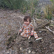 Jose joined the competition — help win amazing prizes! child, toddler, pajamas, fox_pattern, outdoor, nature, rocks, sticks, earth, grass, plants, shoes, dirt, sitting, curious, baby, person, exploring, casual_clothing, daylight