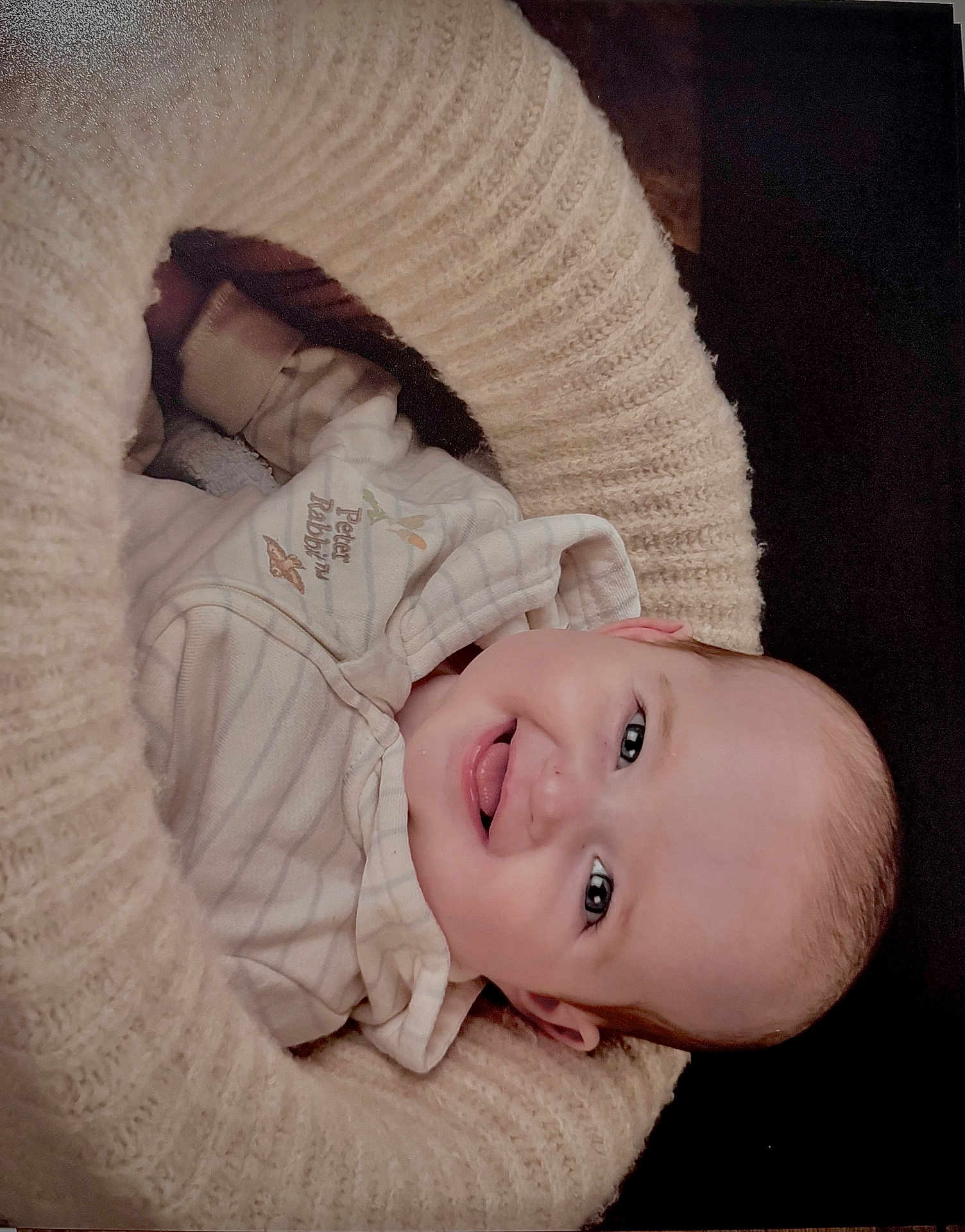 Ace is registered to the contest to win money with this photo: baby, infant, smiling, happy, face, knitted_blanket, cozy, clothing, peter_rabbit, cute, portrait, child, soft, warm, indoor, newborn, head, expression, comfort, sleepwear