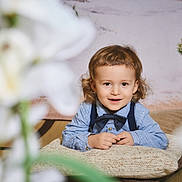 Leonard a rejoint le concours — aidez-le/la à gagner de superbes lots ! child, toddler, bow_tie, striped_shirt, suspenders, pillow, smile, face, portrait, indoor, plant, bonsai, flower_blur, hands, curly_hair, eyes, cozy, cute, cushion, photography