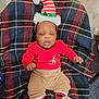 baby, celebration, child, christmas, cozy, cute, decorations, elf_hat, festive, footwear, hat, holiday, indoors, infant, plaid_blanket, portrait, red_clothing, sitting, smiling, sock