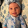 baby, infant, headband, blue, bow, onesie, floral_pattern, blanket, snowflake, pattern, cute, child, face, tongue_out, lying_down, playful, expression, soft_lighting, indoors, portrait