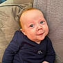 Liam a rejoint le concours — aidez-le/la à gagner de superbes lots ! baby, infant, child, blue_eyes, smile, face, clothing, navy_blue, sitting, pillow, couch, indoor, skin, hand, cute, portrait, young, soft_texture, comfortable, expression