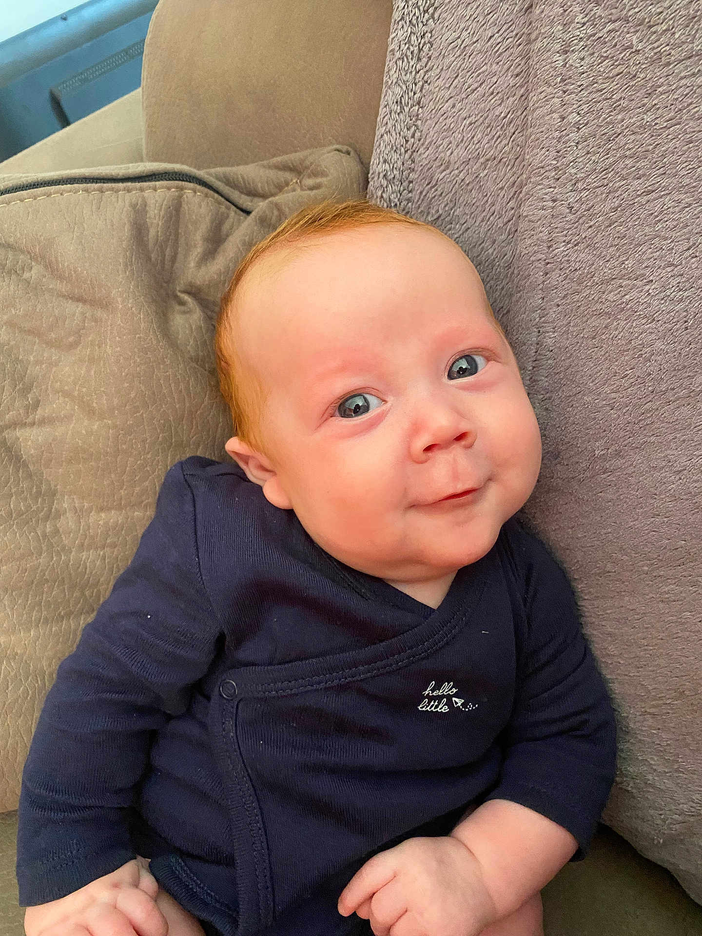 Liam a rejoint le concours — aidez-le/la à gagner de superbes lots ! baby, infant, child, blue_eyes, smile, face, clothing, navy_blue, sitting, pillow, couch, indoor, skin, hand, cute, portrait, young, soft_texture, comfortable, expression