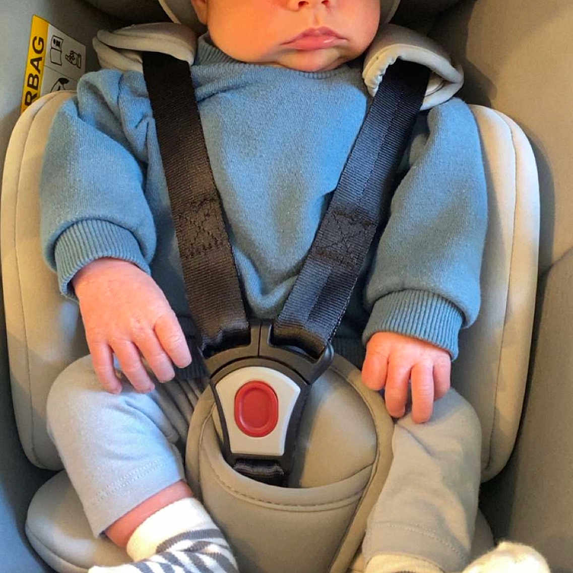 Liam participe au concours pour gagner de l'argent avec cette photo : baby, blue_sweater, car_seat, child, clothing, cute, expression, face, feet, hands, head, indoors, infant, person, portrait, safety, seatbelt, sitting, striped_socks, young_child