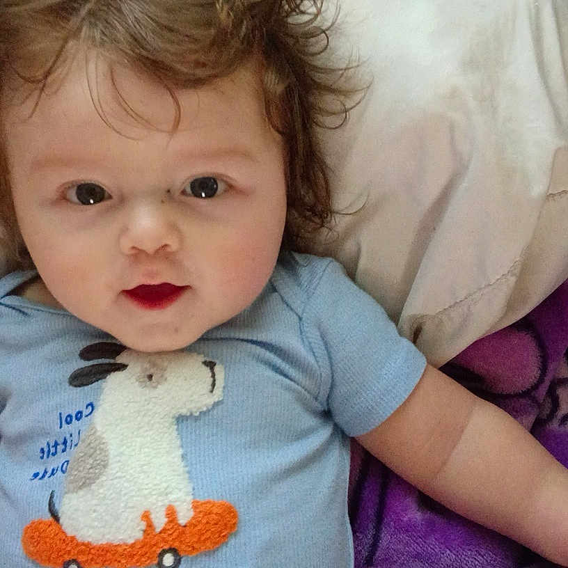 Jaxson joined the competition — help win amazing prizes! baby, infant, child, portrait, lying_down, face, eyes, wide_eyed, smiling, blue_clothing, duck, scooter, pillow, blanket, bed, indoors, close_up, brown_hair, cute, photography