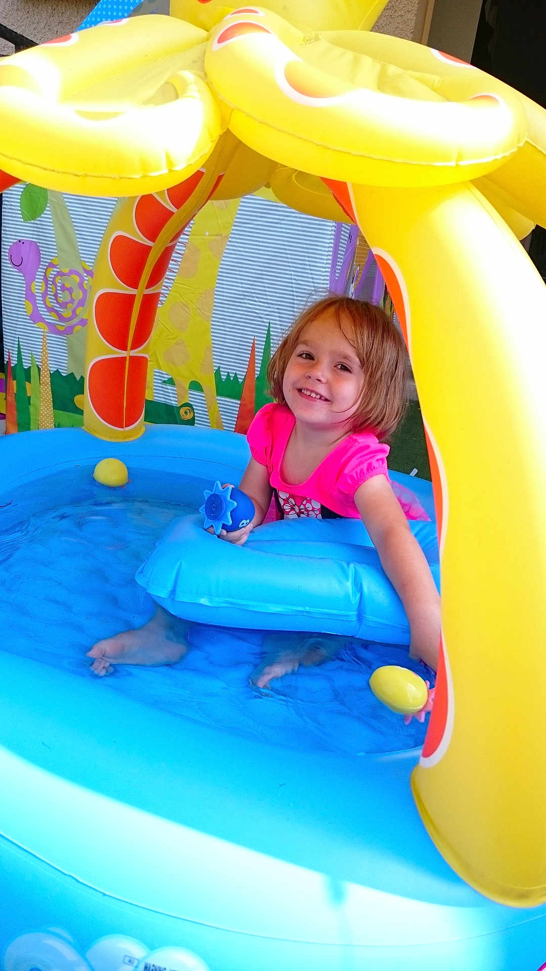 Erin participe au concours pour gagner de l'argent avec cette photo : child, girl, pool, inflatable_pool, water, toy, smile, pink_clothing, yellow_canopy, play, summer, outdoor, happy, feet_in_water, sunlight, floating_toy, blue_pool, playful, cute, recreation