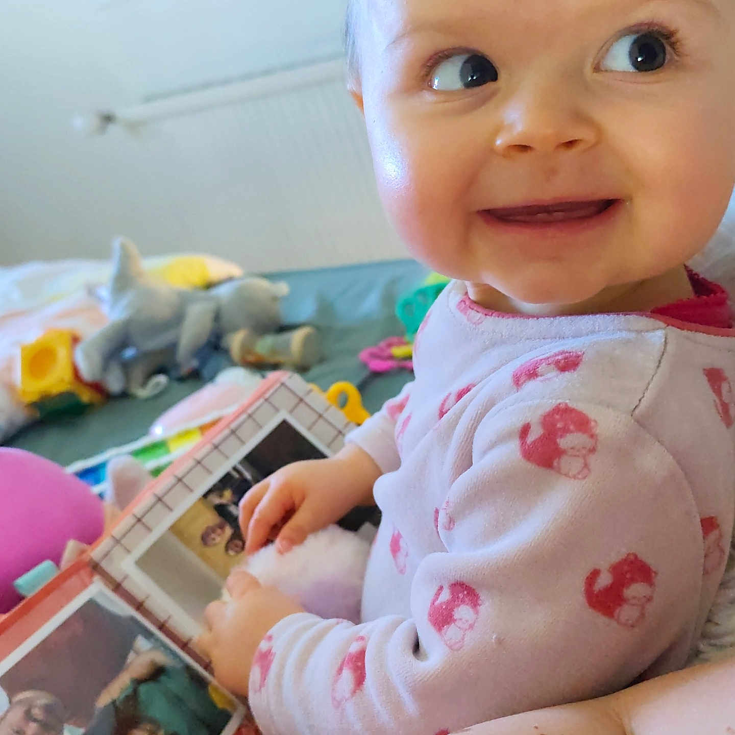 Soline participe au concours pour gagner de l'argent avec cette photo : baby, child, pajamas, photo_album, smile, face, hand, indoor, toy, furniture, curious, person, playtime, young_child, infant, home, sitting, looking_away, cute, cozy