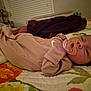 baby, infant, pacifier, onesie, bed, blanket, quilt, floral_pattern, sleepwear, lying_down, indoor, child, person, bedroom, soft_lighting, curious_expression, home, cuddly, resting, cozy