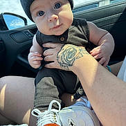 Lincoln joined the competition — help win amazing prizes! baby, child, infant, beanie, hat, tattoo, hand, car_interior, window, shoe, sneaker, clothing, person, portrait, cute, holding, seat, daylight, face, curious