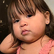 Madeline is registered to the contest to win money with this photo: toddler, child, girl, portrait, close_up, face, bangs, brown_hair, earring, pink_dress, sleeveless, chubby_cheeks, expressionless, eyes, lips, skin, indoor, candid, background_wall, young_child