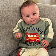 Elyo participe au concours pour gagner de l'argent avec cette photo : baby, blanket, car_graphic, child, couch, cozy, expression, eyes, hair, hands, home_interior, infant, lamp, pajamas, portrait, sitting, smiling, sofa, soft_texture, sweater