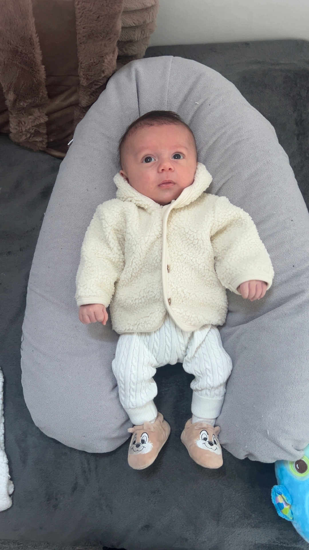 Elyo participe au concours pour gagner de l'argent avec cette photo : baby, cartoon, child, comfortable, curious, cushion, cute, face, gray, indoor, infant, knitted_clothing, person, plush, sitting, slippers, soft, toy, warm_clothing, white_clothing