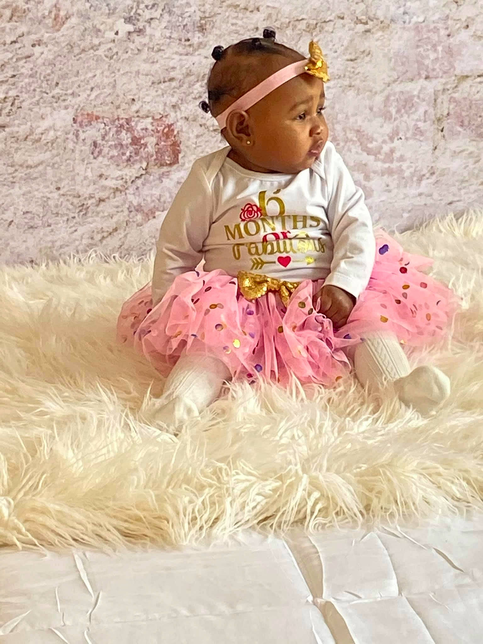 Kelani joined the competition — help win amazing prizes! baby, baby_toddler_clothing, beanie, cap, child, costume_accessory, fashion_design, fun, grass, happy, headgear, magenta, pattern, peach, people_in_nature, person, play, sitting, sleeve, sunglasses