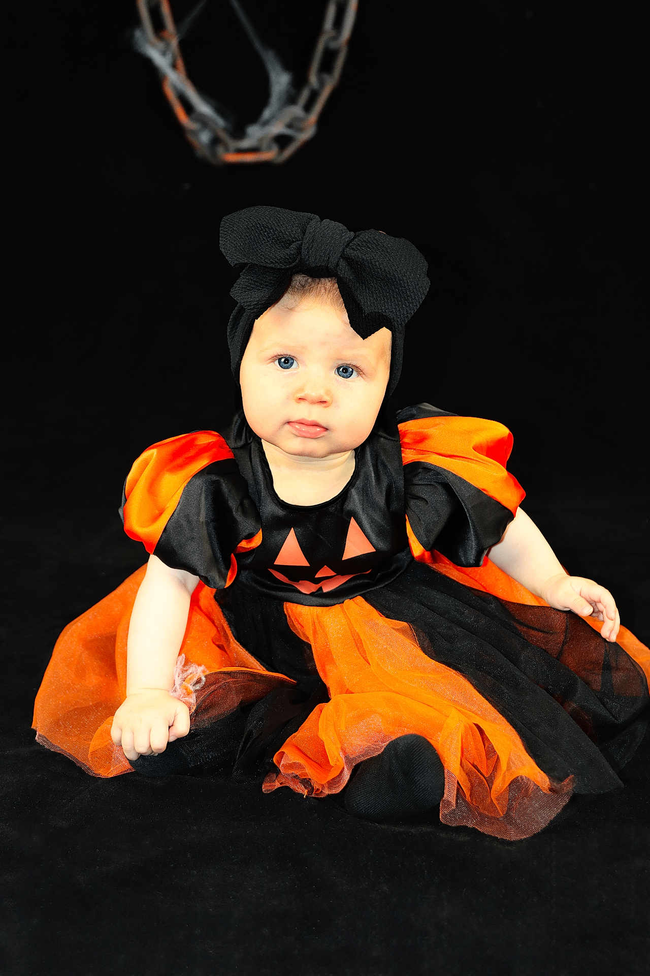 Athénaïs a rejoint le concours — aidez-le/la à gagner de superbes lots ! baby, child, costume, halloween, pumpkin, black, orange, dress, headband, bow, sitting, portrait, cute, blue_eyes, infant, holiday, festive, studio, photography, dark_background