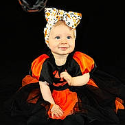Athénaïs participe au concours pour gagner de l'argent avec cette photo : baby, child, halloween, dress, headband, bow, orange, black, costume, sitting, portrait, cute, smiling, face, blue_eyes, infant, background, chain, holiday, festive