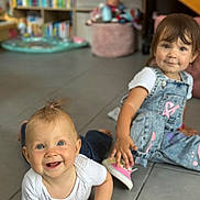 Henrya participe au concours pour gagner de l'argent avec cette photo : baby, toddler, child, floor, denim_overalls, white_shirt, pink_shoes, smiling, indoor, playroom, toy, bookshelf, tile_floor, person, happy, cute, candid, young_child, casual_clothing, home