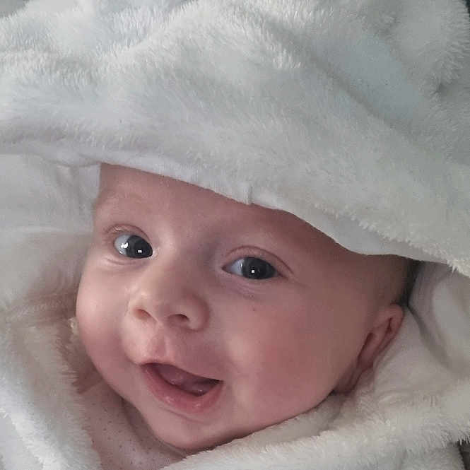 Aria is registered to the contest to win money with this photo: baby, blanket, bonnet, clothing, face, happy, hat, head, hood, hoodie, knitwear, newborn, person, photography, portrait, quilt, smile, sweater, sweatshirt, towel