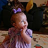 baby, blue_eyes, child, closeup, couch, curious, hair_bow, hand_on_face, home, indoors, play_mat, playroom, portrait, purple_bow, purple_dress, red_hair, sitting, soft_lighting, thoughtful, toddler