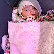 Amélia participe au concours pour gagner de l'argent avec cette photo : baby, sleeping, blanket, hat, pacifier, stroller, cozy, child, infant, soft, pink, floral, resting, peaceful, cute, warm, tucked_in, portrait, indoors, comfort