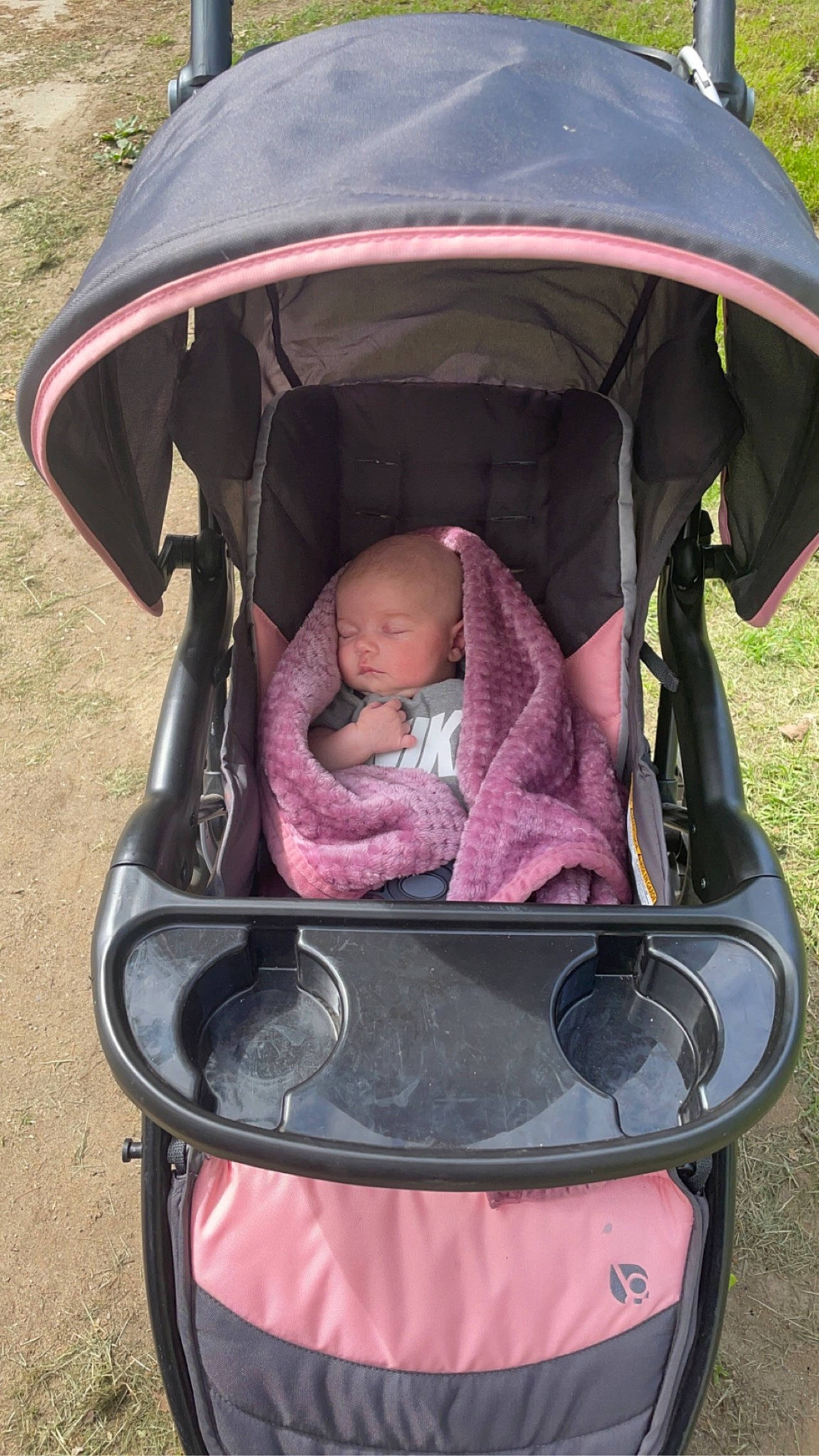 Marcella is registered to the contest to win money with this photo: baby, baby_carriage, baby_products, baby_toddler_clothing, child, comfort, fashion_accessory, fun, grass, green, leisure, motor_vehicle, person, personal_protective_equipment, pink, plant, product, sitting, tire, toddler