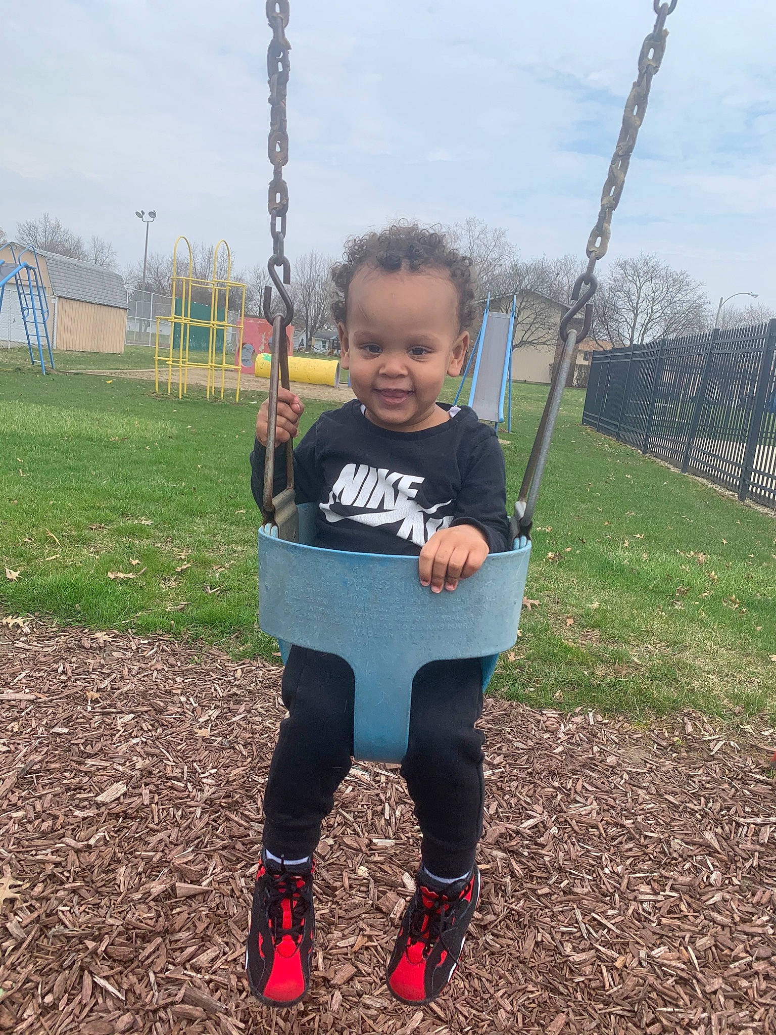 Mekhi joined the competition — help win amazing prizes! child, city, fun, happy, joy, outdoor_play_equipment, person, plant, play, playground, public_space, recreation, sky, smile, swing, t_shirt, toddler, tree