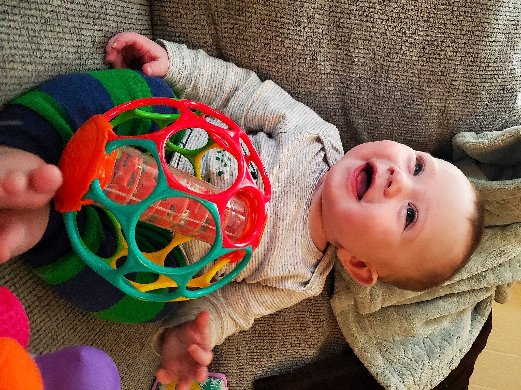 Grant is registered to the contest to win money with this photo: art, baby, baby_toddler_clothing, ball, child, football, fun, green, linens, mammal, orange, ornament, pattern, person, smile, soccer_ball, sports_toy, textile, toddler, toy