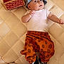 Jack is registered to the contest to win money with this photo: baby, infant, child, hat, cap, white_shirt, orange_pants, polka_dots, checkered_shoes, vans_shoebox, footwear, mattress, quilted, indoor, cute, fashion, relaxed, lying_down, young, apparel