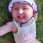 Iris a rejoint le concours — aidez-le/la à gagner de superbes lots ! baby, grass, hat, tank_top, smiling, tongue_out, outdoor, child, cute, sunlight, polka_dot, infant, playful, happy, apparel, headwear, nature, person, summer, closeup