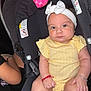 baby, child, car_seat, yellow_clothing, headband, bracelet, infant, chubby, cute, indoor, person, seatbelt, black_seat, pink_toy, expressionless, wrists, legs, skin, closeup, portrait