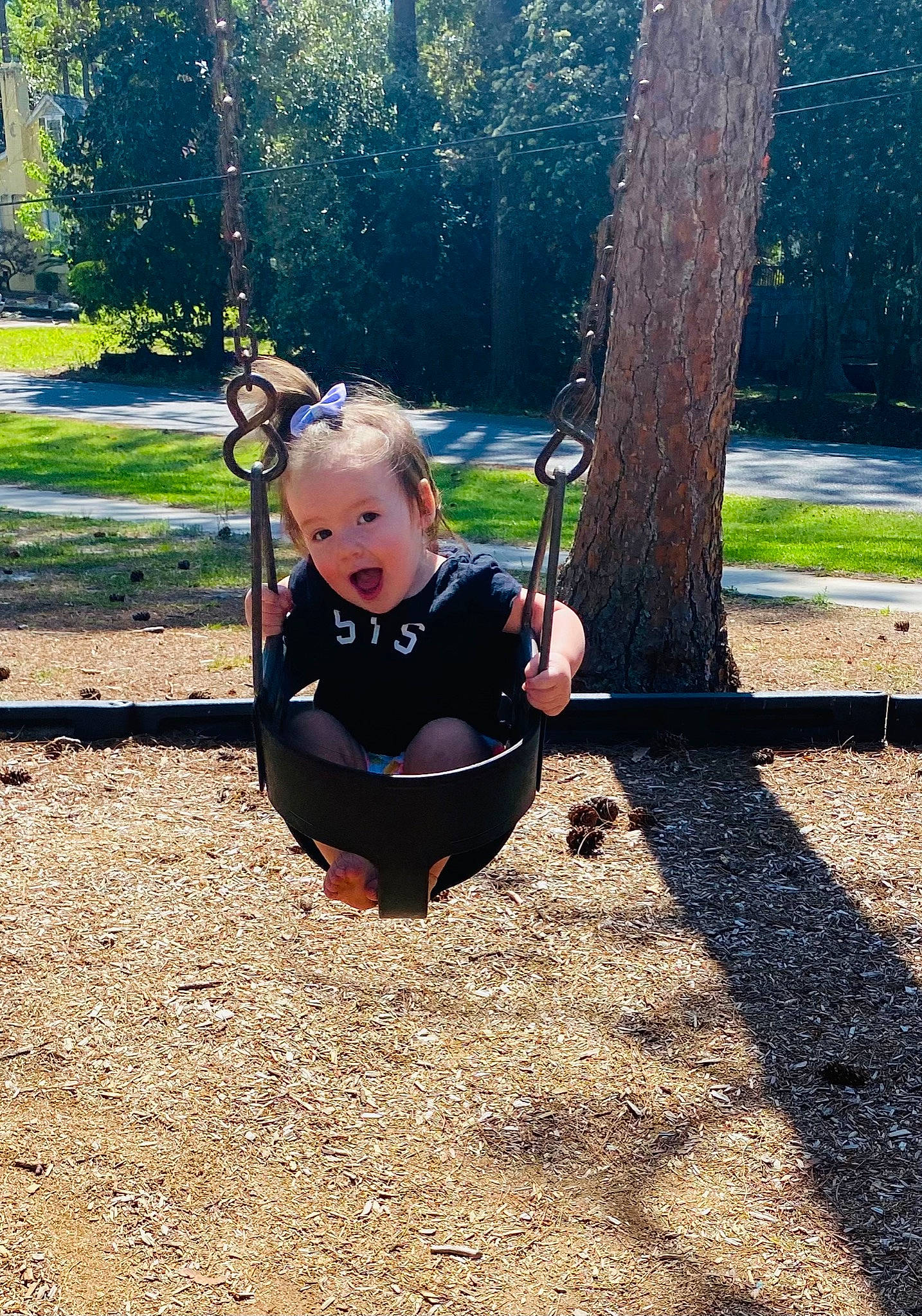 Annika is registered to the contest to win money with this photo: baby, child, city, fun, grass, leaf, leisure, outdoor_play_equipment, people_in_nature, person, plant, play, playground, recreation, shade, sitting, soil, swing, tints_and_shades, toddler