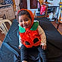 black_tablecloth, chair, child, costume, cozy, curly_hair, curtains, furniture, happy, home, indoor, orange, person, playful, pumpkin_costume, smiling, socks, table, toddler, window