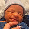Akari is registered to the contest to win money with this photo: newborn, baby, infant, sleeping, smiling, face, portrait, knit_cap, striped_hat, blue_clothing, blanket, cozy, indoors, close_up, adult_hand, fingers, caregiver, soft_lighting, peaceful, family