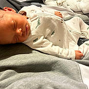 Akari is registered to the contest to win money with this photo: newborn, baby, sleeping, infant, child, portrait, indoors, blanket, clothing, onesie, dinosaur_print, bed, soft, cozy, peaceful, resting, face, closed_eyes, photography, cute