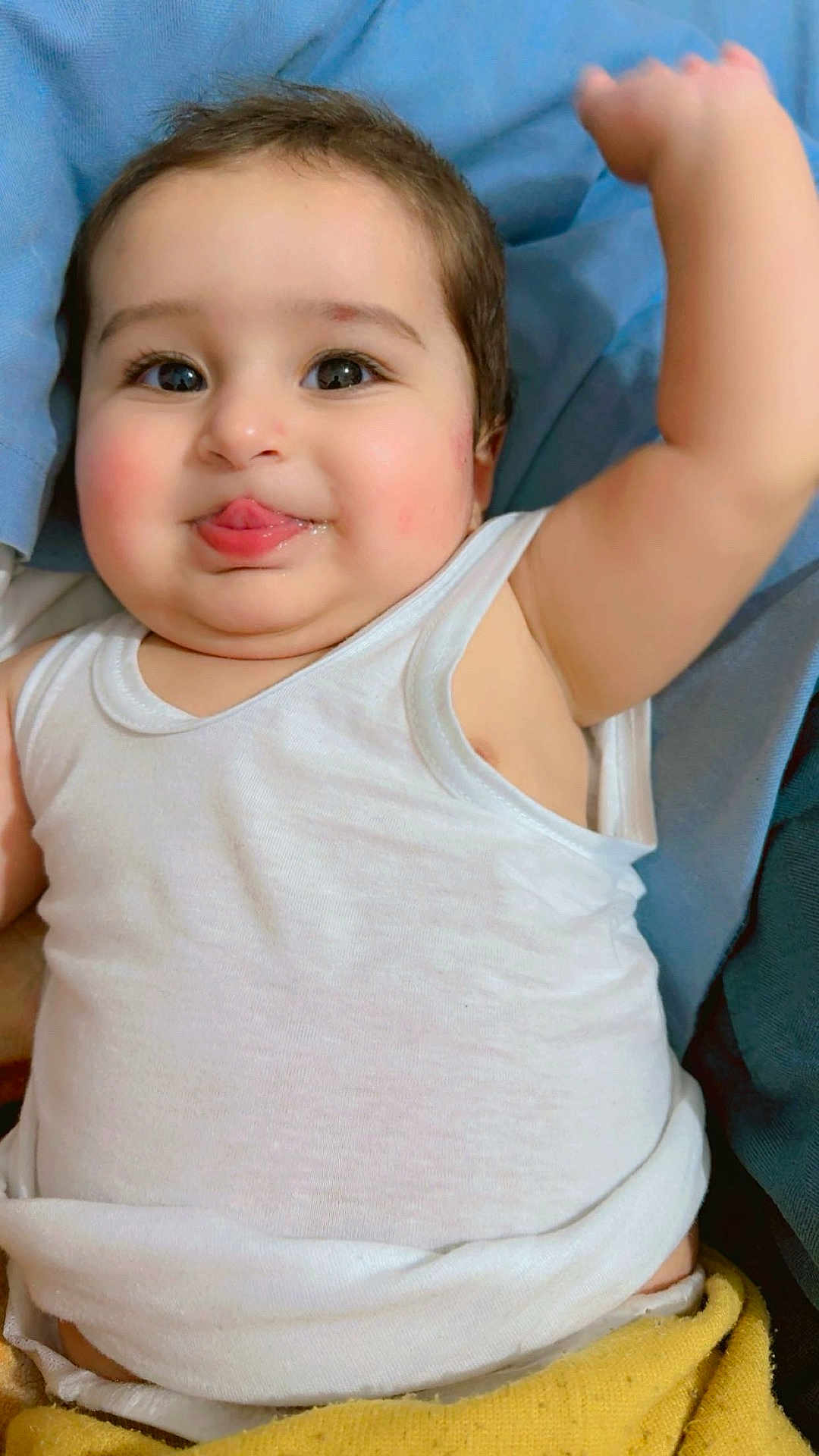 Muhammad joined the competition — help win amazing prizes! baby, child, tongue, white_tank_top, arm_raised, cheeks, face, skin, eyes, hair, blanket, fabric, soft, cute, expression, lying_down, indoors, infant, smile, playful