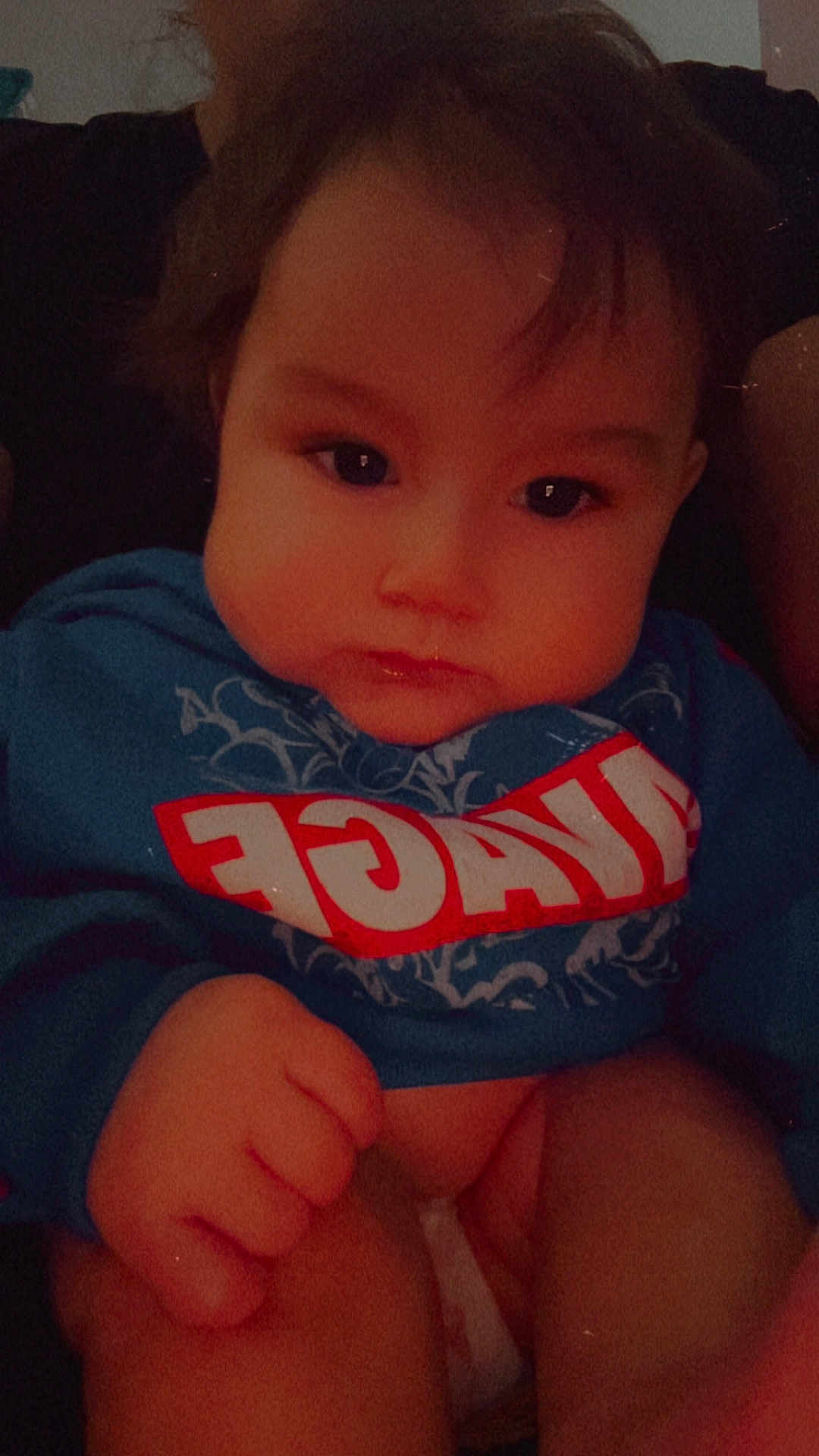 Lucian is registered to the contest to win money with this photo: baby, infant, child, face, cheeks, eyes, hair, hoodie, clothing, diaper, hand, fist, portrait, closeup, indoors, sitting, cute, chubby, expression_serious, soft_lighting