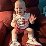 baby, child, sitting, armchair, red, white, shoes, socks, shorts, tshirt, smiling, motion_blur, indoor, furniture, face, person, cute, happy, waving, plush
