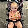 baby, child, stroller, smiling, indoor, carpet, people, clothing, seat, hand, face, happy, patterned, transportation, waiting_area, luggage, casual, light_hair, infant, toddler