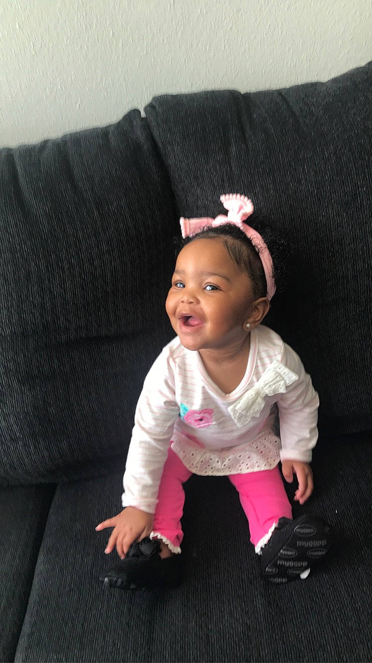 Zoey is registered to the contest to win money with this photo: baby, baby_toddler_clothing, cheek, child, collar, comfort, couch, fashion_accessory, happy, linens, lip, magenta, person, pink, portrait_photography, sitting, sleeve, smile, t_shirt, textile