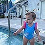 toddler, child, swimsuit, pool, water, unicorn, pigtails, outdoor, summer, playful, wet, blue, concrete, building, sky, clouds, palm_tree, handrail, happy, feet