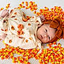 Evelyn is registered to the contest to win money with this photo: baby, infant, candy_corn, pumpkin_outfit, headband, brown_bow, cute, lying_down, white_background, holiday_theme, fall, autumn, soft_texture, baby_clothing, child, portrait, sweet, colorful, festive, holiday