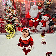 Samira is registered to the contest to win money with this photo: toddler, child, santa_hat, christmas_outfit, holiday_decor, balloon, number_9, christmas_tree, snowman, santa_claus, gift_boxes, festive, smiling, indoor, carpet, red_clothing, white_fur_trim, celebration, cute, christmas_theme