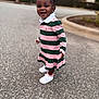 toddler, child, smiling, outdoor, paved_road, dress, striped_clothing, pink, green, hair_bows, white_sneakers, earrings, happy, standing, person, curb, blurred_background, nature, daylight, fashion