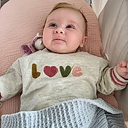 Anna participe au concours pour gagner de l'argent avec cette photo : baby, infant, child, face, sweater, love_text, blanket, pink_cushion, knitted, blue_blanket, lying_down, indoors, cute, young_child, portrait, cozy, soft_texture, sleeping_area, hand, expression