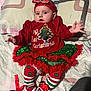 baby, child, christmas, holiday, festive, tutu, headband, bedspread, clothing, red, green, striped_leggings, booties, cute, infant, smiling, person, laying, indoors, holiday_outfit