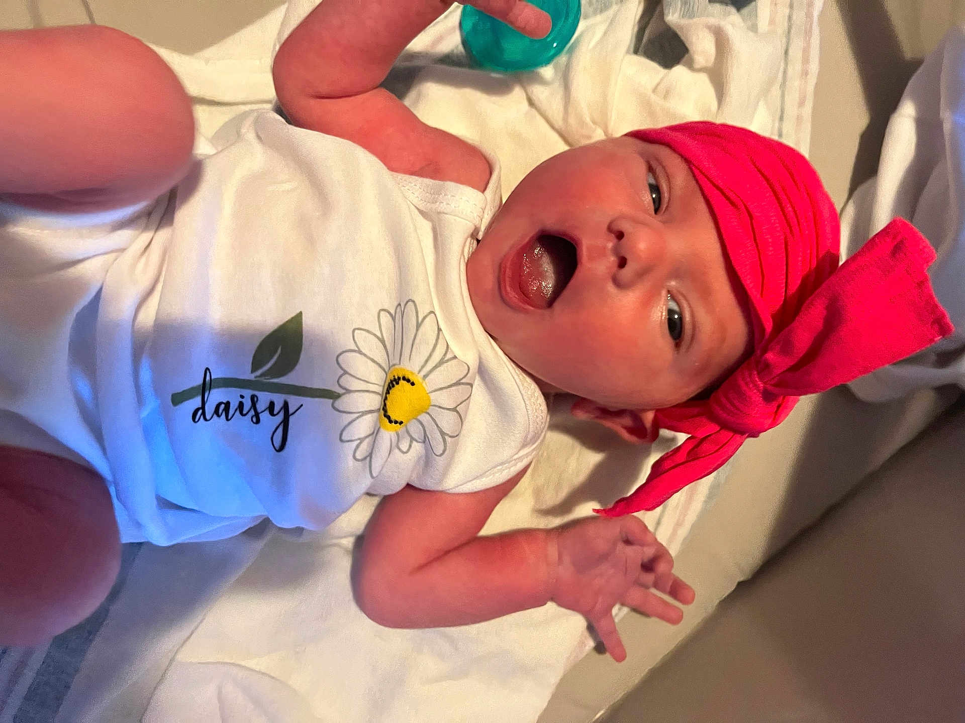 Cierra is registered to the contest to win money with this photo: baby, infant, head_wrap, onesie, daisy, flower, pink, white, lying_down, hand, face, open_mouth, cute, soft_surface, skin, newborn, child, expression, clothing, portrait