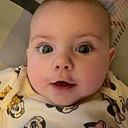 Cierra is registered to the contest to win money with this photo: baby, face, close_up, expression, eyes, infant, clothing, cartoon_characters, minnie_mouse, cute, soft, indoors, child, young, portrait, smiling, apparel, person, baby_girl, lying_down