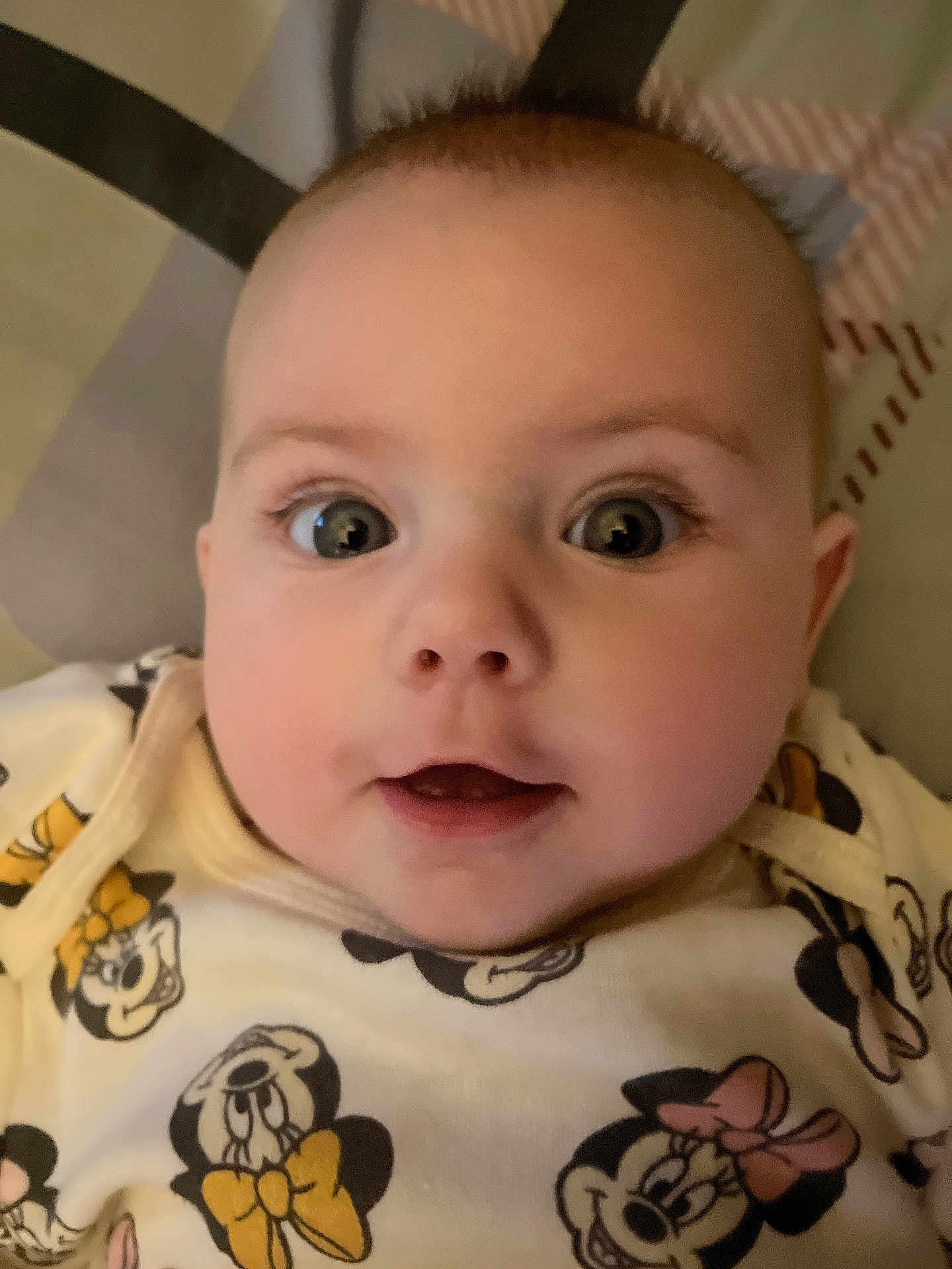 Cierra is registered to the contest to win money with this photo: baby, face, close_up, expression, eyes, infant, clothing, cartoon_characters, minnie_mouse, cute, soft, indoors, child, young, portrait, smiling, apparel, person, baby_girl, lying_down